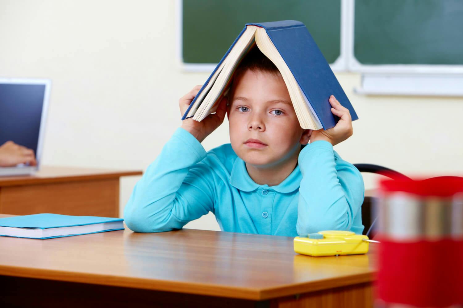Niño en la escuela mostrando signos de inatención, un síntoma común del trastorno por déficit de atención e hiperactividad (TDAH)
