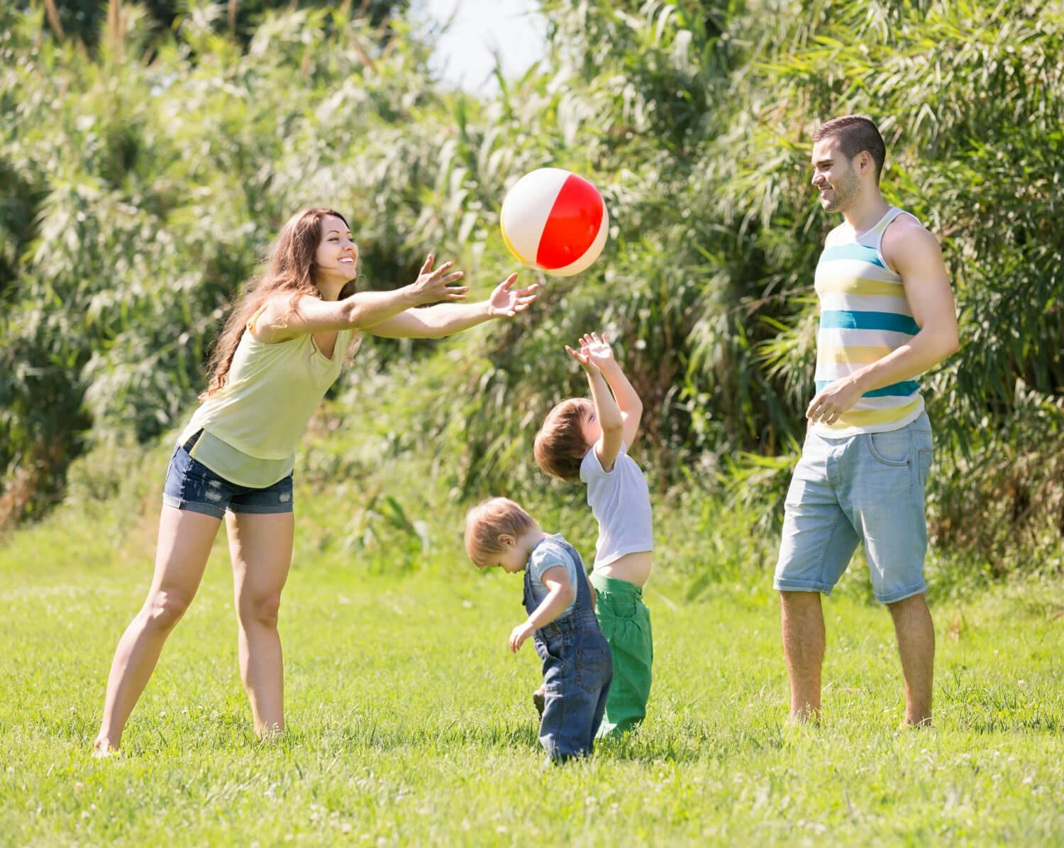 Familia feliz jugando en el parque, representando la importancia del apoyo familiar en el desarrollo de los niños con autismo.